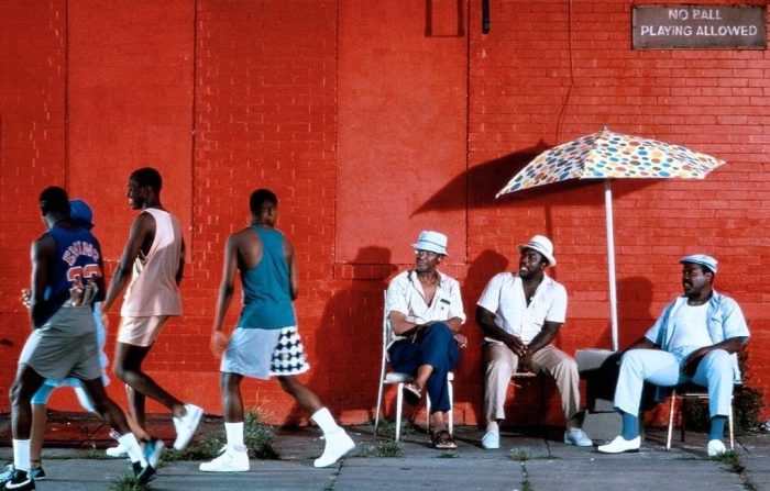 3 hombres negros sentados mirando a otros 3 en un dia de verano