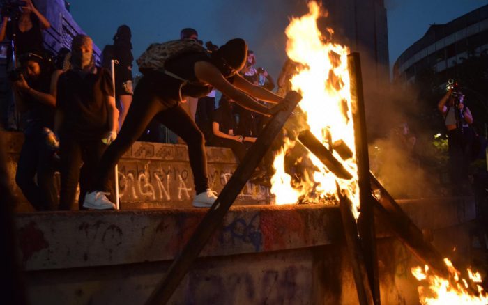 Mujeres encapuchadas encendiendo un fuego