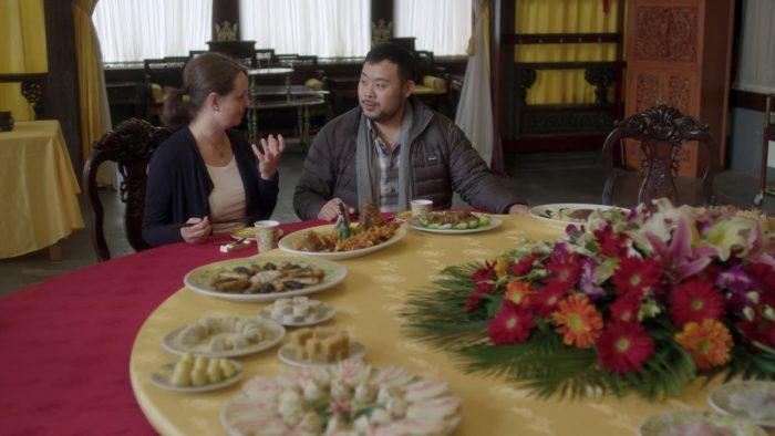 david chang hablando con una mujer en una gran mesa circular con muchos platillos