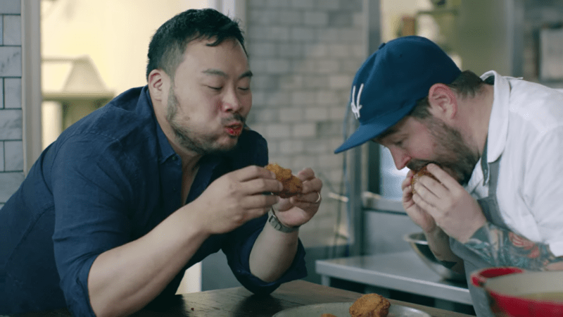 chef coreano david chang comiendo pollo frito con otro chef