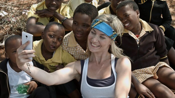mujer blanca tomandose una selfie con mucho niños africanos