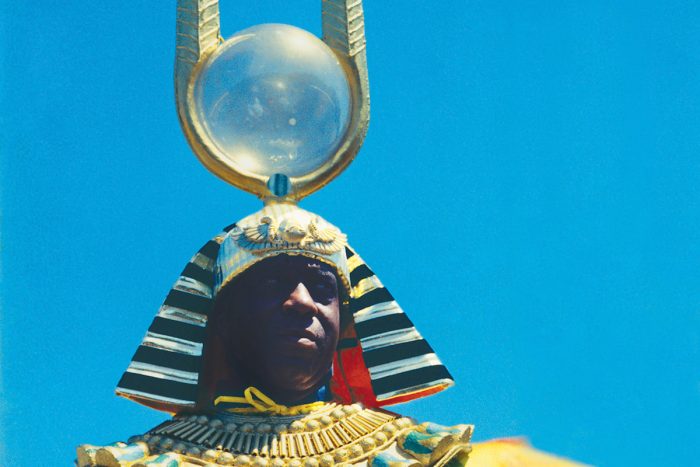 Hombre negro con un traje egipcio y un casco con una gran antena con una bola de cristal